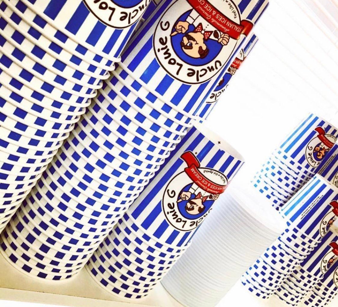 Stacks of Uncle Louie G's ice cream cups, blue and white striped, with logo.