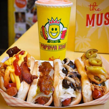Papaya King hot dogs with toppings and drink. Yellow, sunny branding.