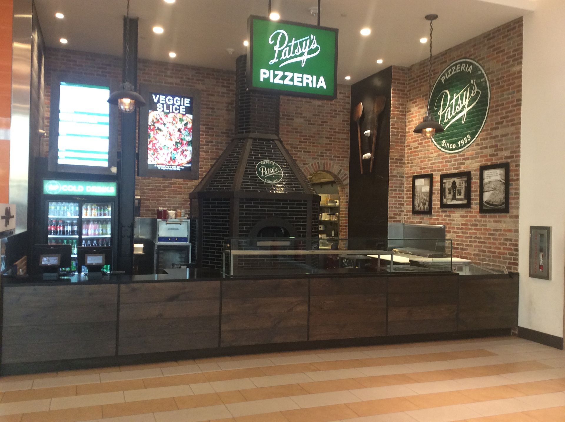 Patty's Pizzeria restaurant with brick wall, pizza oven, and counter in a shopping mall.
