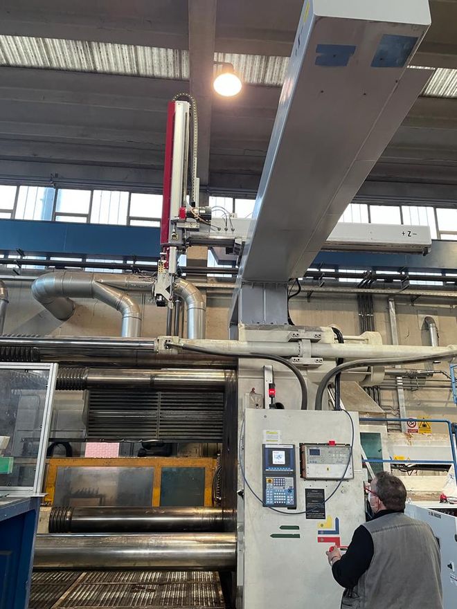 Un trabajador inspecciona los controles junto a una gran máquina industrial en una fábrica.