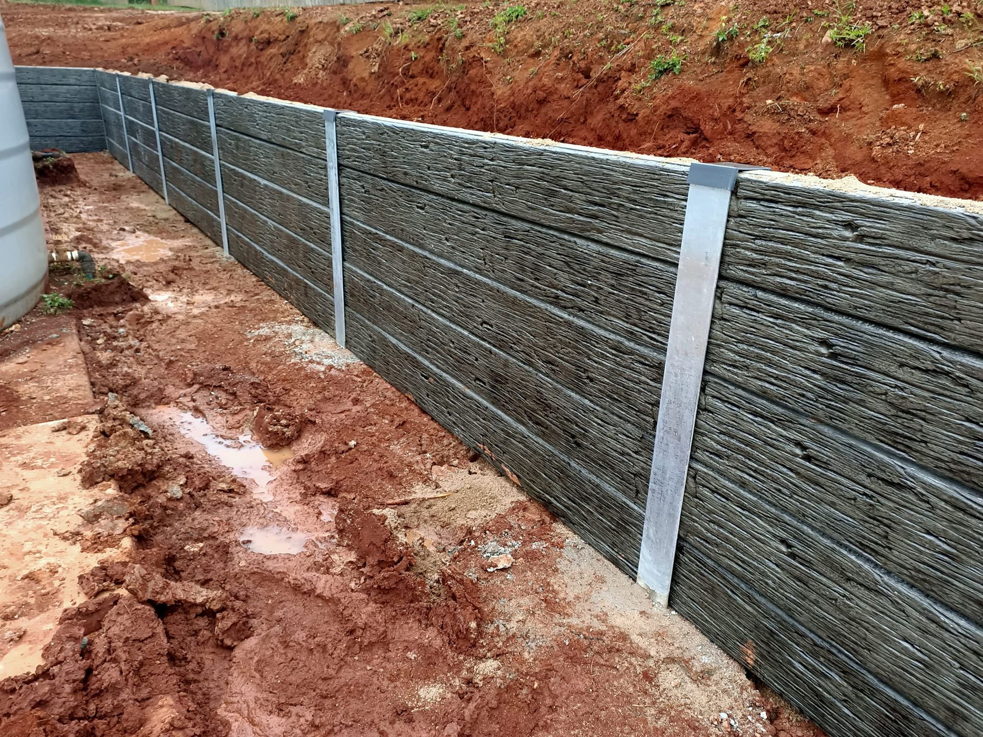 Retaining Wall Constructed With Dark Grey Horizontal Planks — Quality Fences 4 U in Gympie, QLD