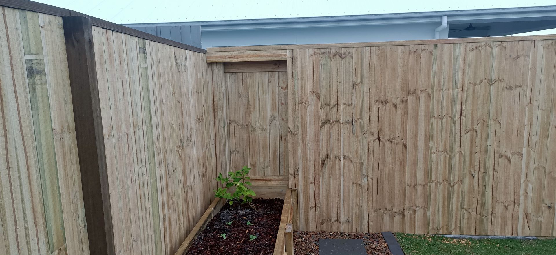 Wooden Backyard Fence And Gate With A Small Planter Bed And Potted Plants In The Corner — Quality Fences 4 U in Gympie, QLD