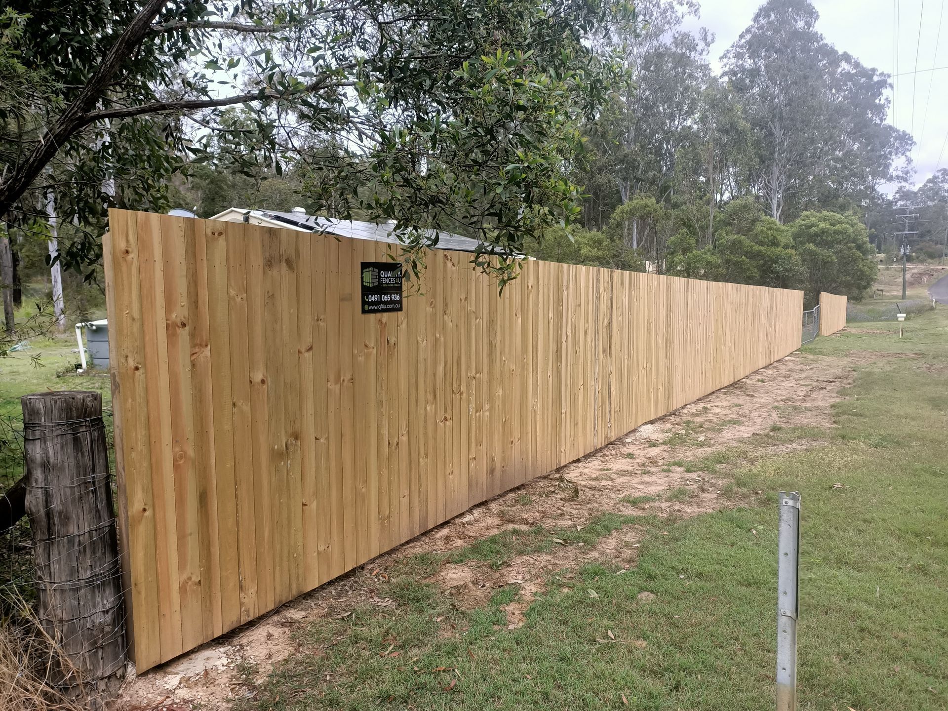 Long Wooden Fence Beside A Grassy Path Under Trees On A Cloudy Day — Quality Fences 4 U in Gympie, QLD