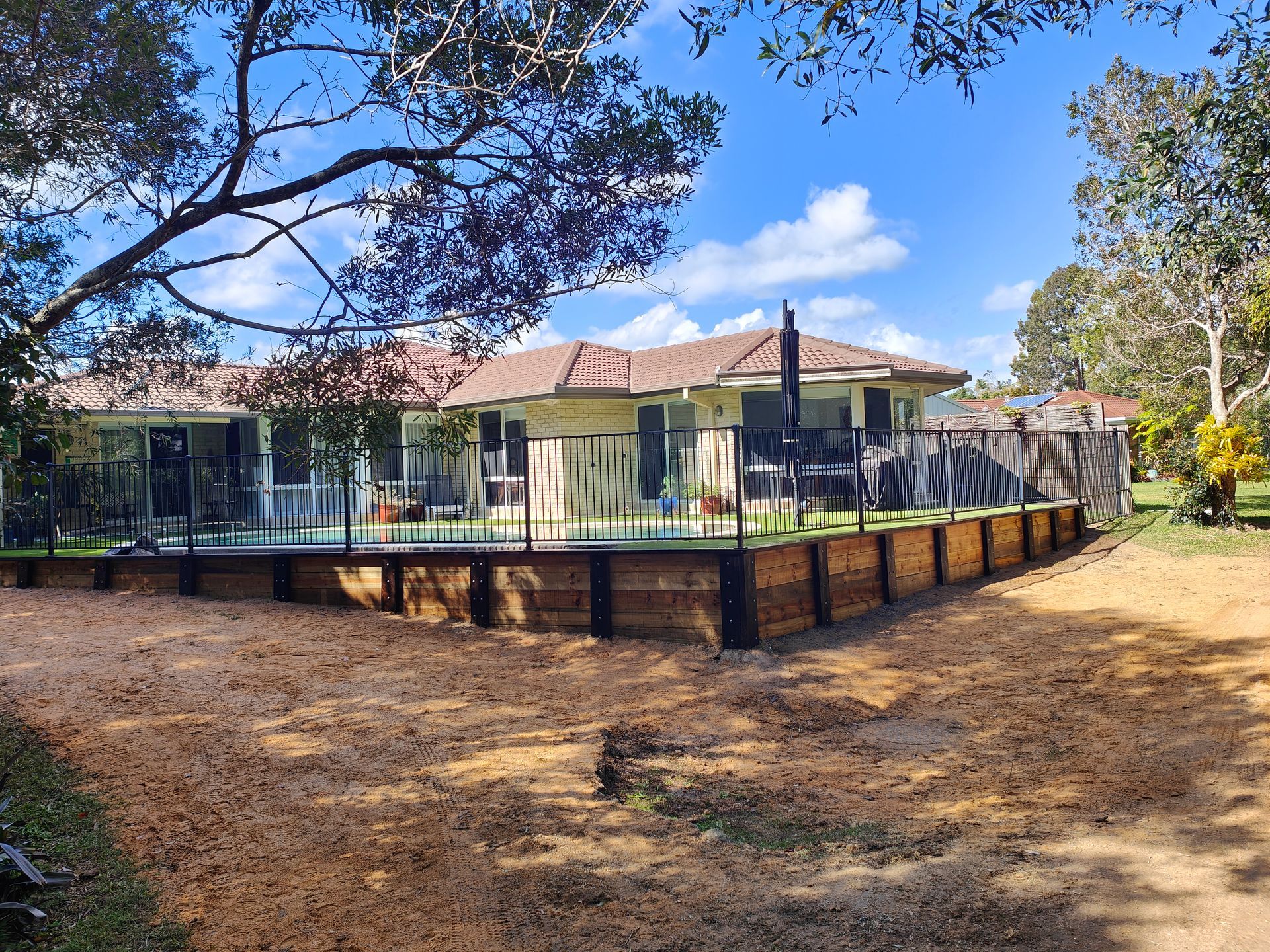 Modern House With Glass Walls And A Raised Deck Surrounded By Dry Yard And Trees — Quality Fences 4 U in Gympie, QLD