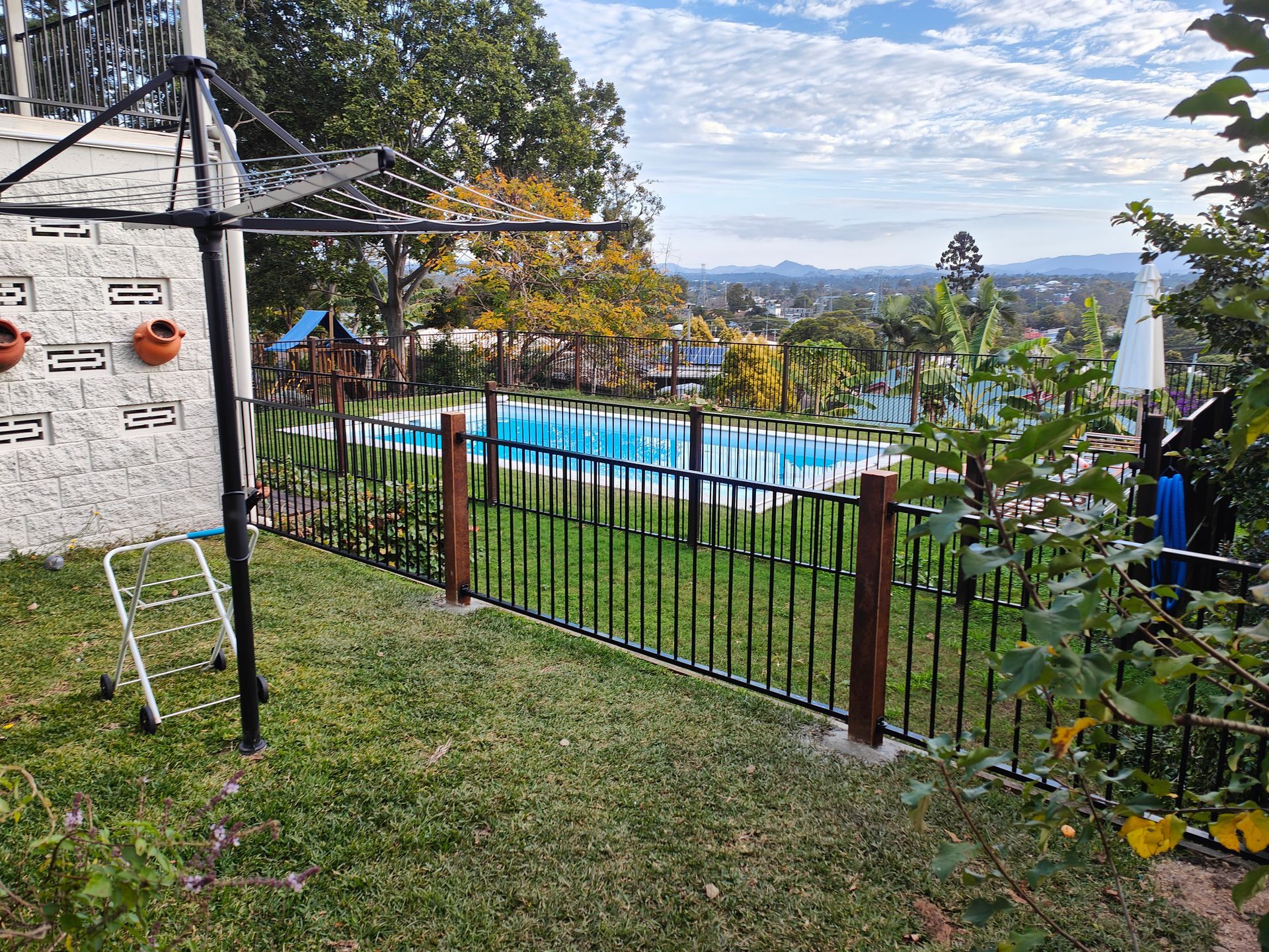 Backyard With Fenced Pool, Grassy Lawn, Patio Umbrella, And Distant Mountain View — Quality Fences 4 U in Gympie, QLD