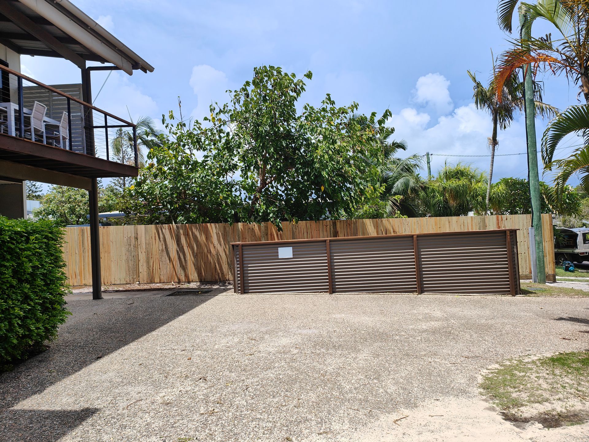 Gravel Yard With A Slatted Wooden Fence, Trees, And A Two-story Building On The Left — Quality Fences 4 U in Gympie, QLD