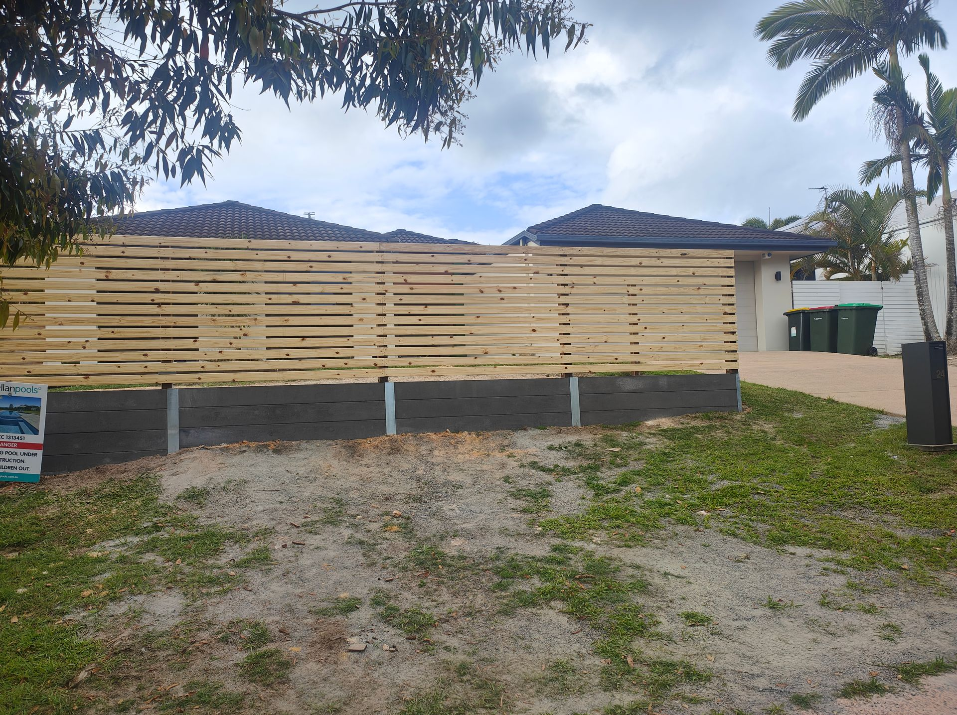 Partially Built Wooden Fence In Front Of A House With Palm Trees And A Sandy Yard — Quality Fences 4 U in Gympie, QLD