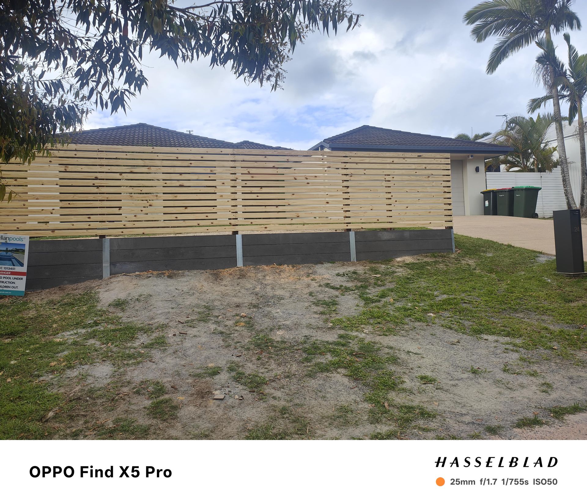 Wooden fence in front of a house, set on concrete blocks, with a grassy area in the foreground and a cloudy sky — Quality Fences 4 U in Gympie, QLD