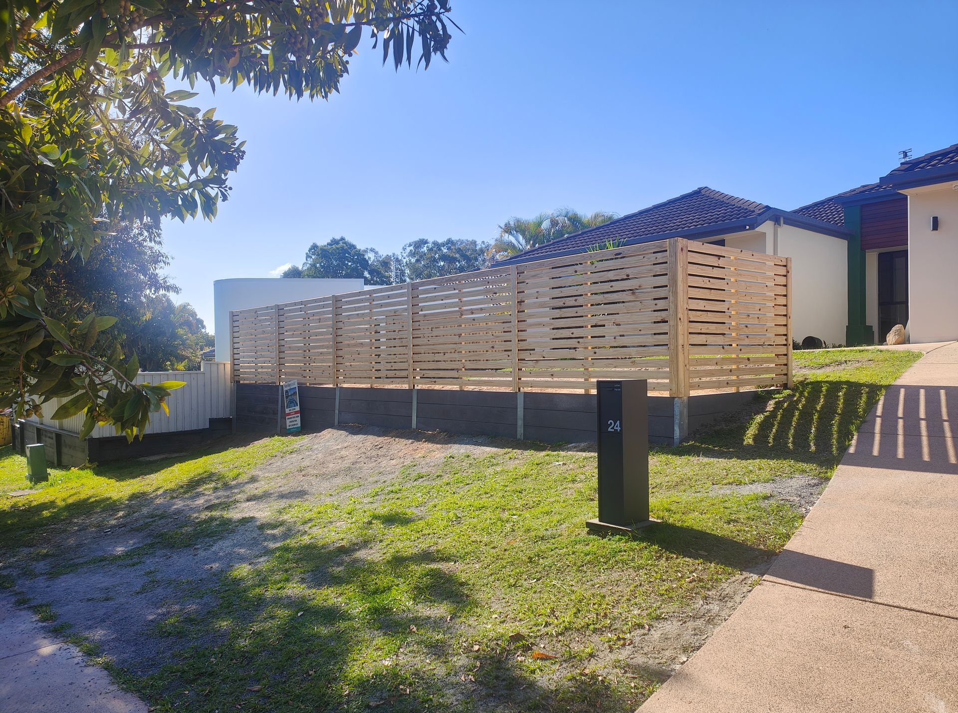 Modern House With A Wooden Fence, Gravel Yard, And Driveway In Bright Sunlight — Quality Fences 4 U in Gympie, QLD