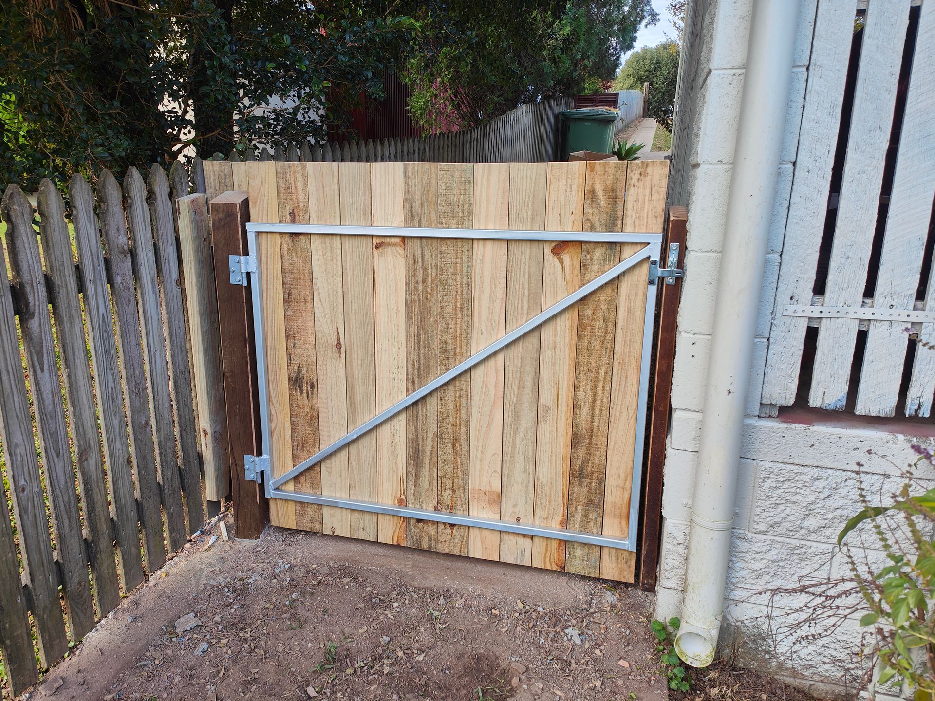 Wooden Gate With Metal Braces Between Fences At The Side Of A House — Quality Fences 4 U in Gympie, QLD