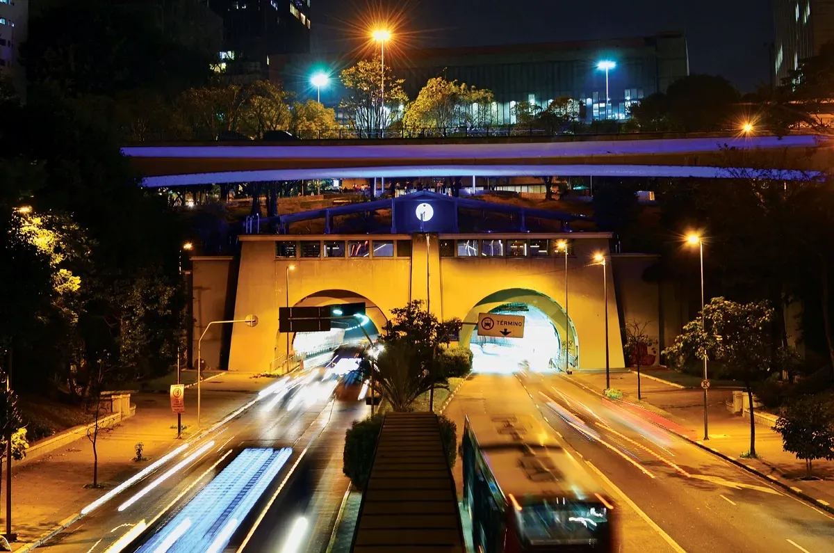 Um ônibus está passando por baixo de uma ponte à noite