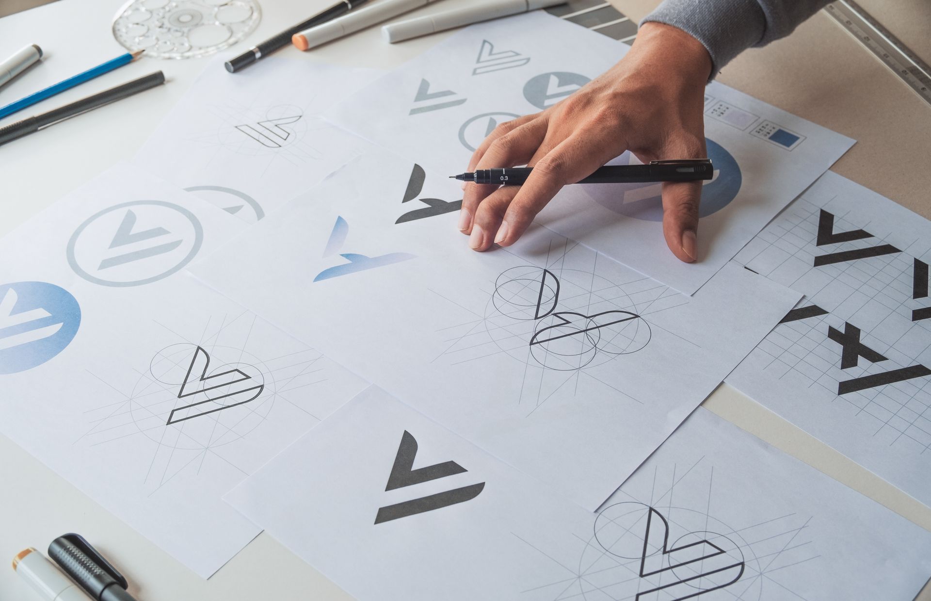 Eine Person zeichnet mit einem Stift ein Logo auf ein Blatt Papier.