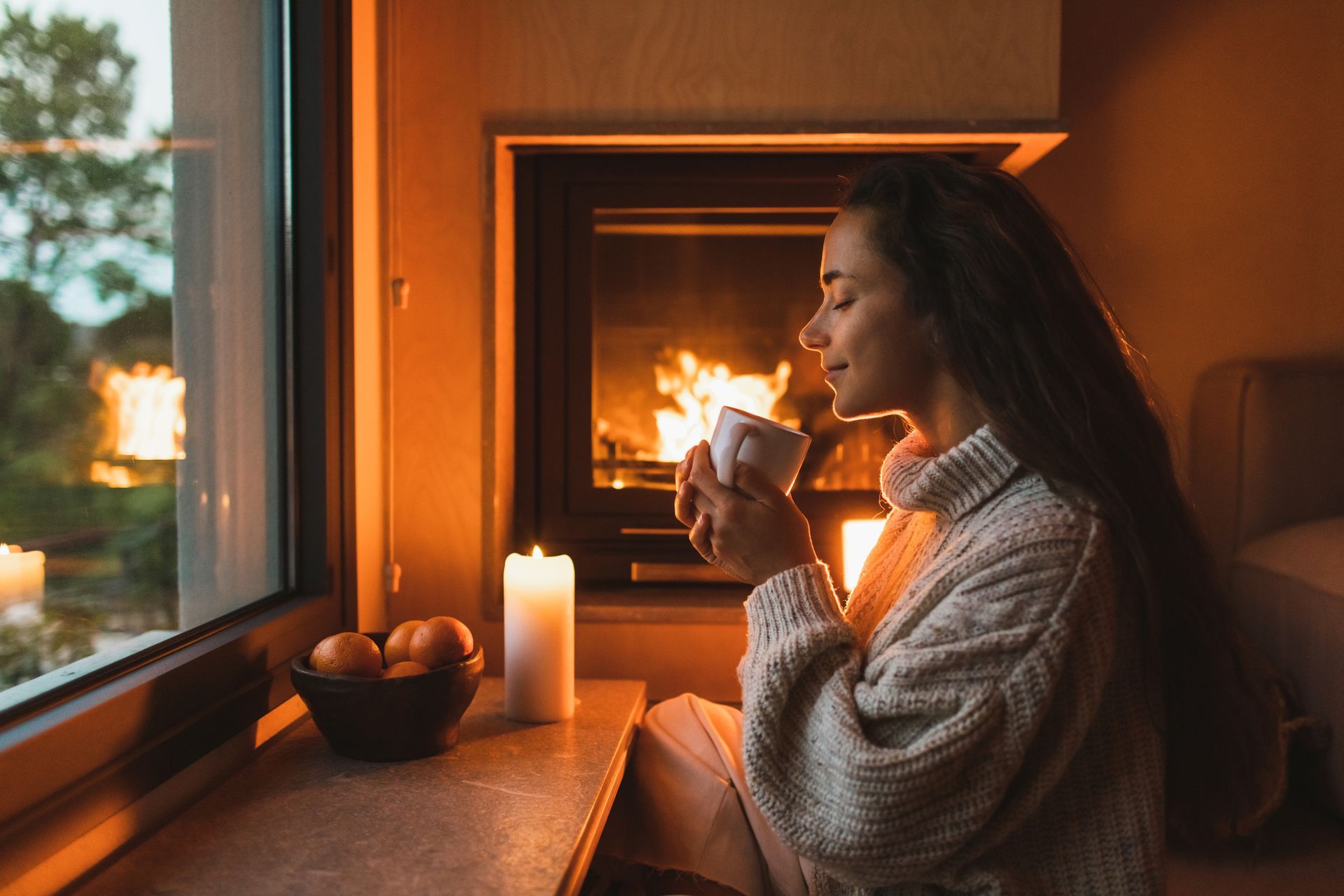 Smiling woman in woolen sweater drinking warm tea at home near fireplace – Macungie, PA - Anytime Todd's Chimney Sweeping