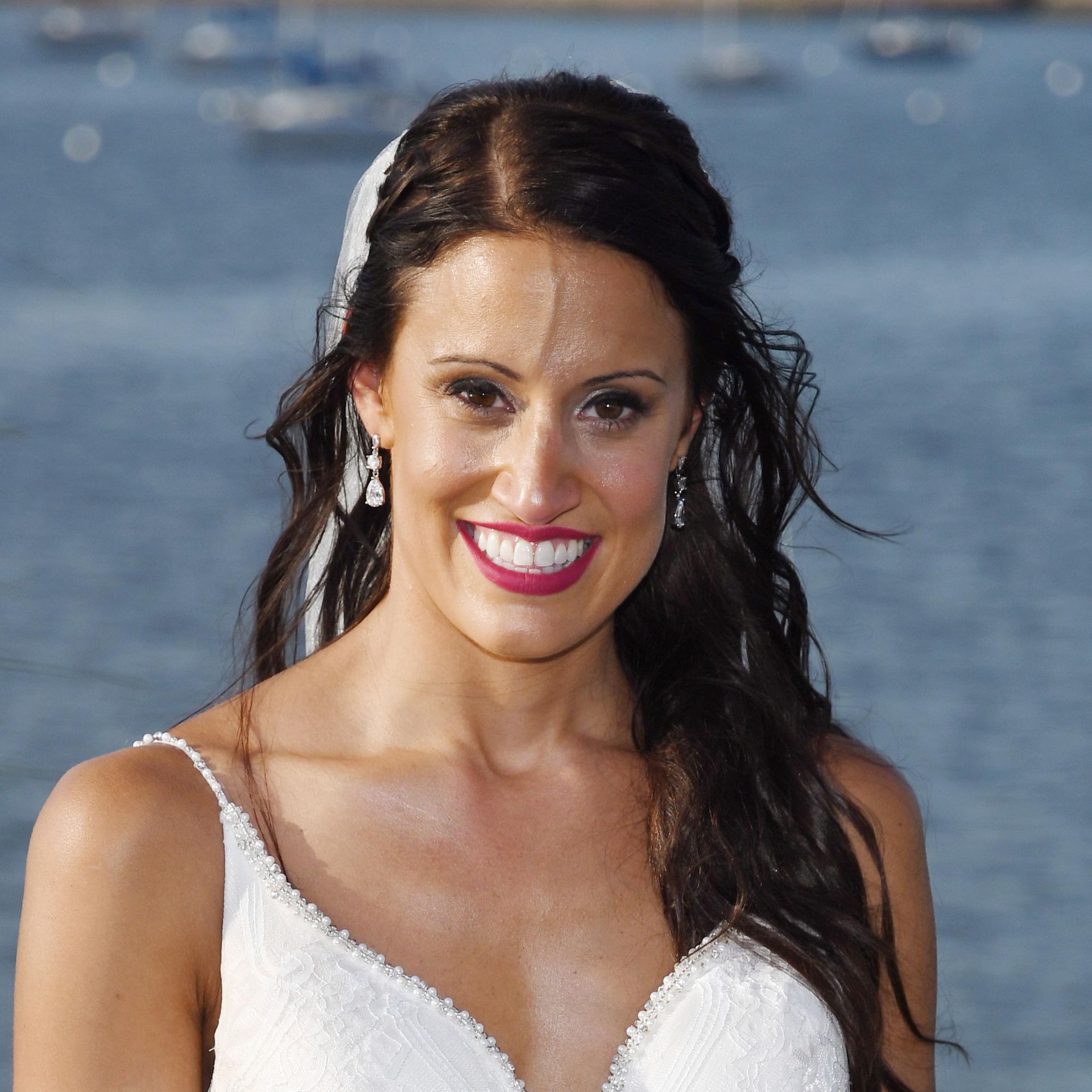 Smiling Bride in a white dress standing by the water