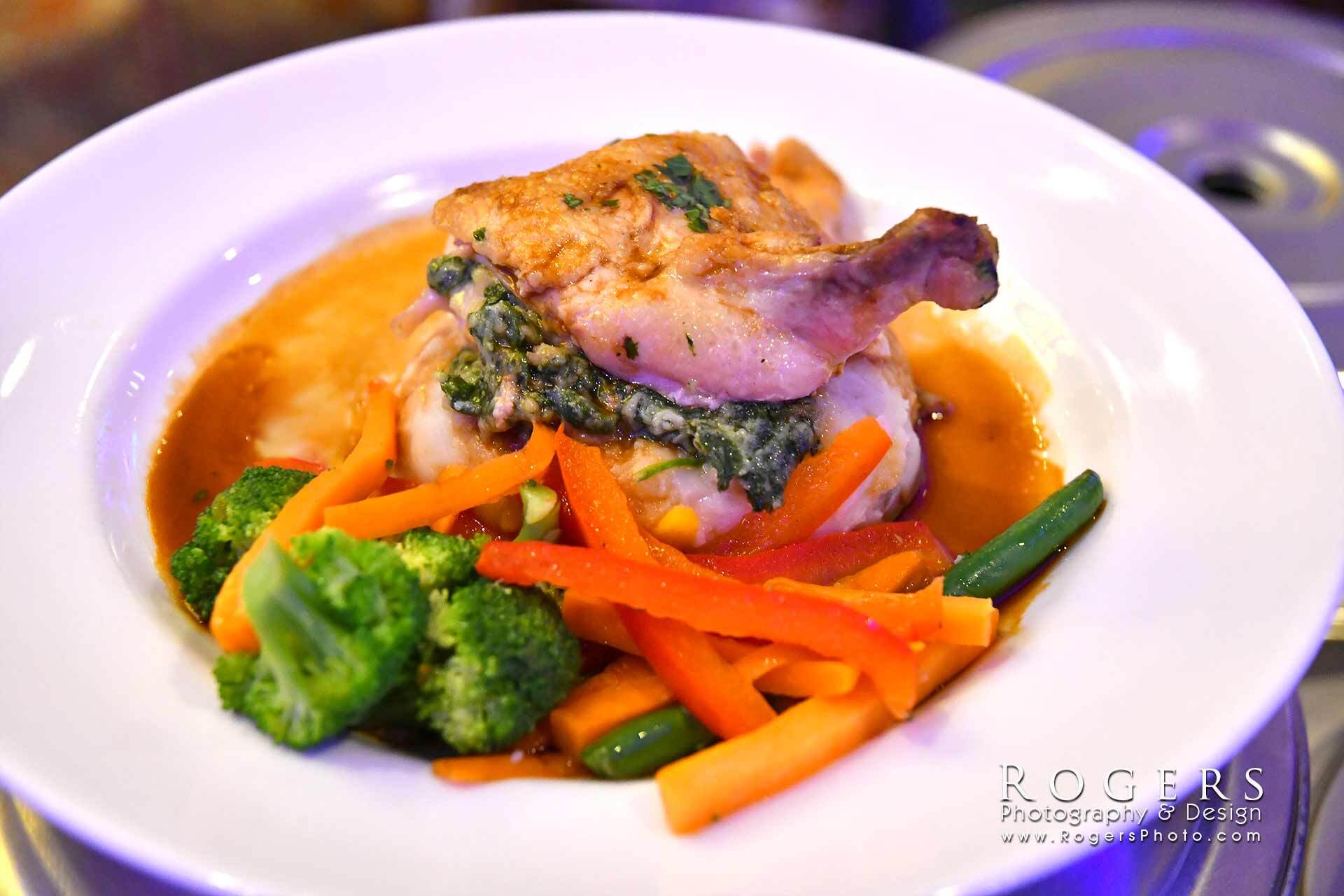 Plated roasted meat with vegetables in sauce on a white dinner plate