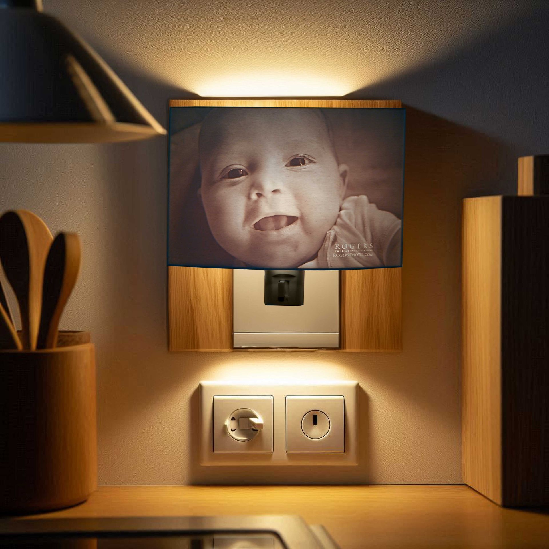 Baby photo on a bedside table with a lamp, outlet, and warm ambient lighting