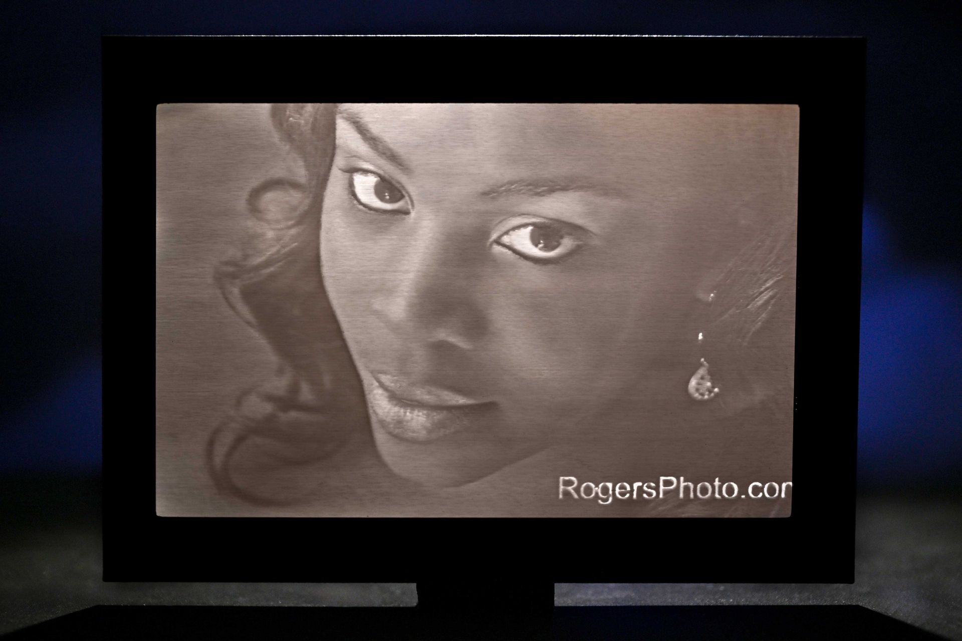 Sepia-toned portrait of a woman with a soft smile and earrings, framed on a dark background