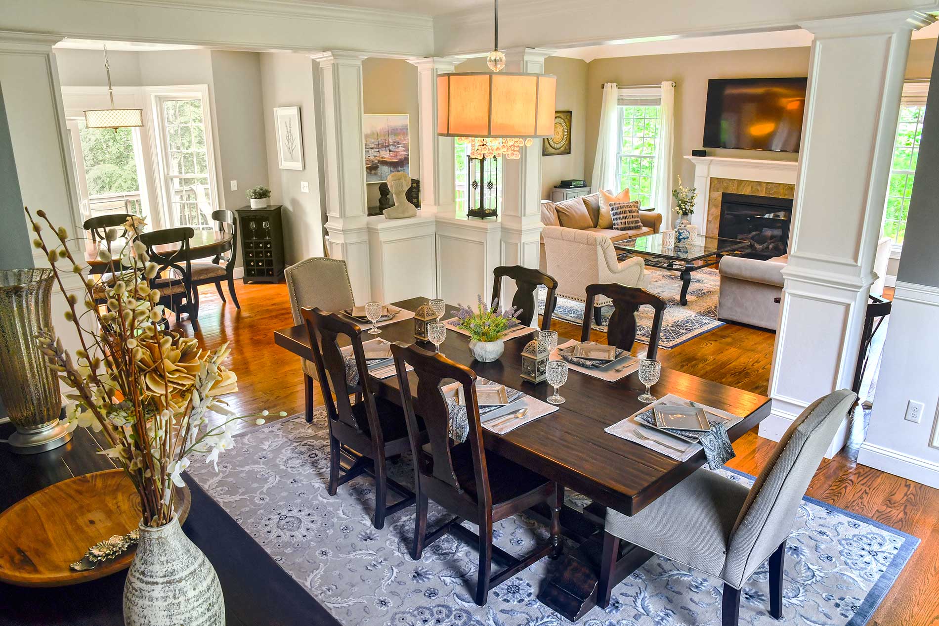 Elegant dining room with dark wood table, upholstered chairs, chandelier, and bright windows