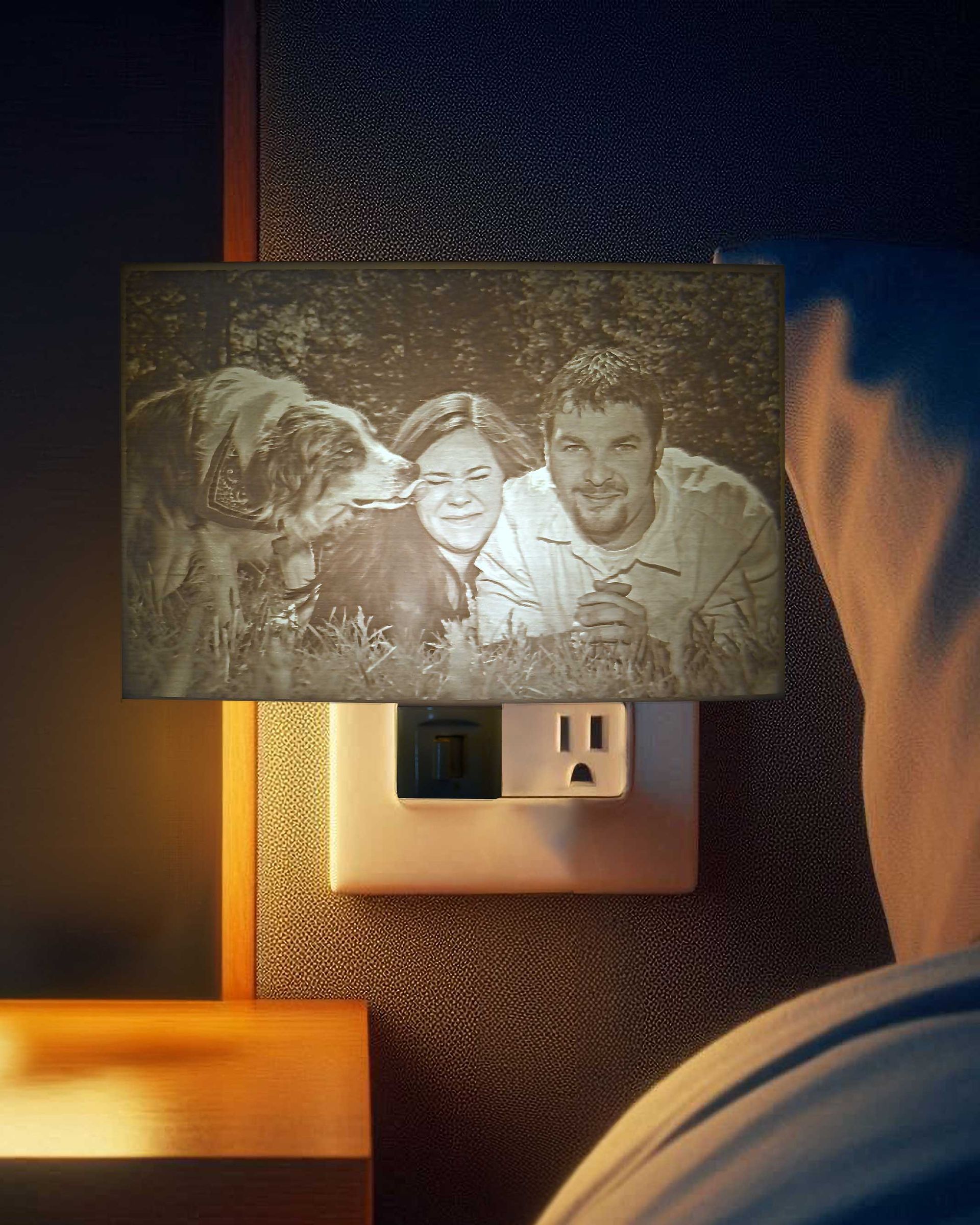 Small photo on a wall beside a bed, showing a smiling family with a dog.