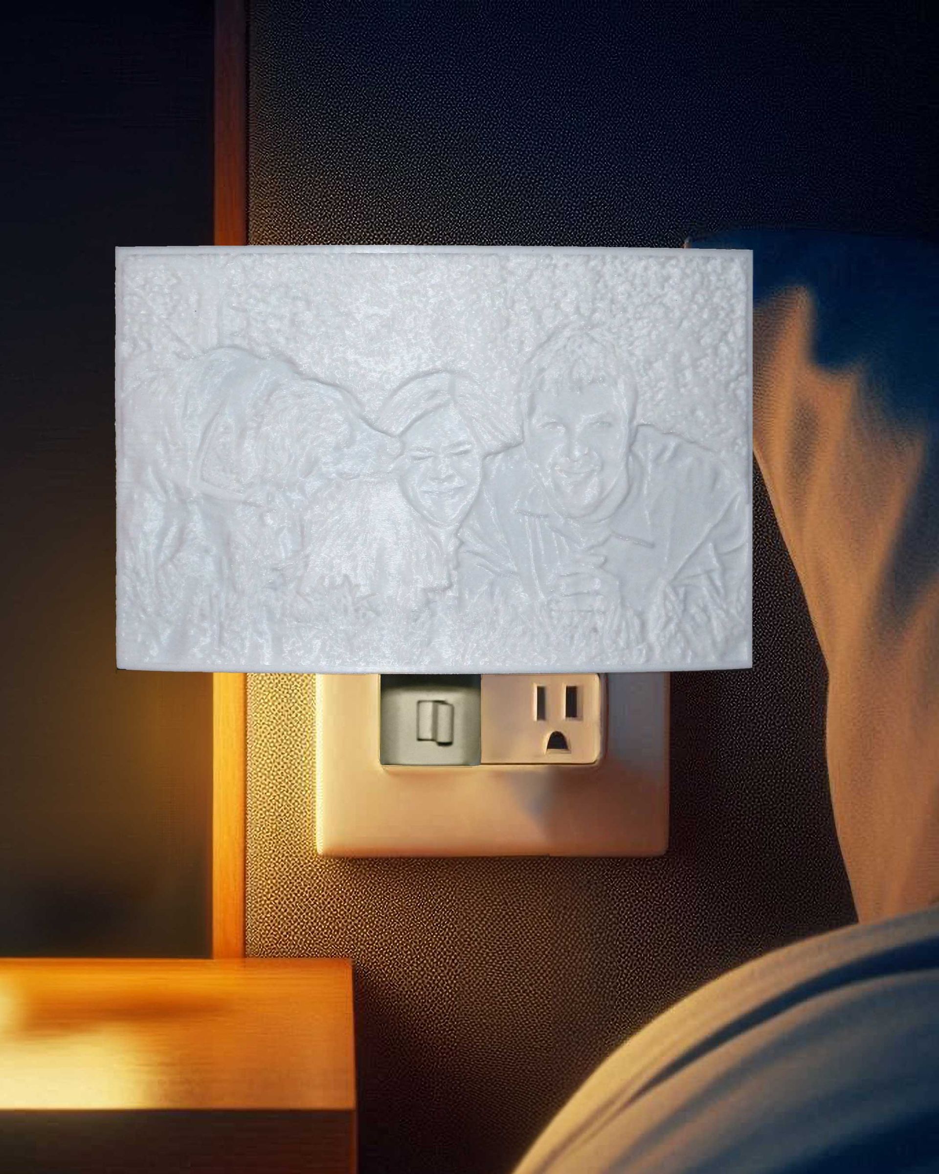 Nightlight cover glowing above a wall outlet beside a bed, casting warm light in a dark room
