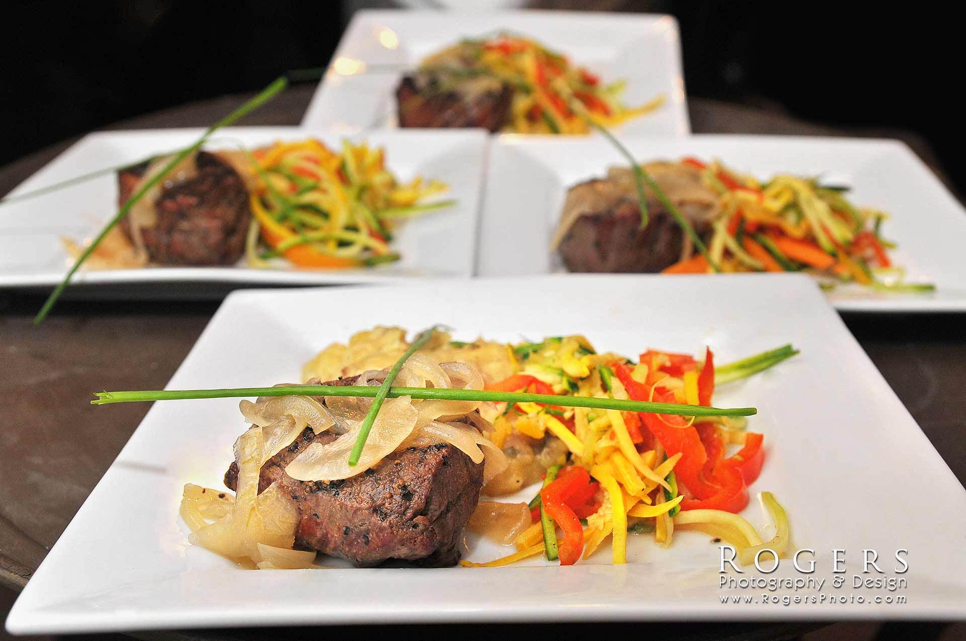 Plated gourmet steak with vegetables on white dishes, arranged in a restaurant-style presentation.