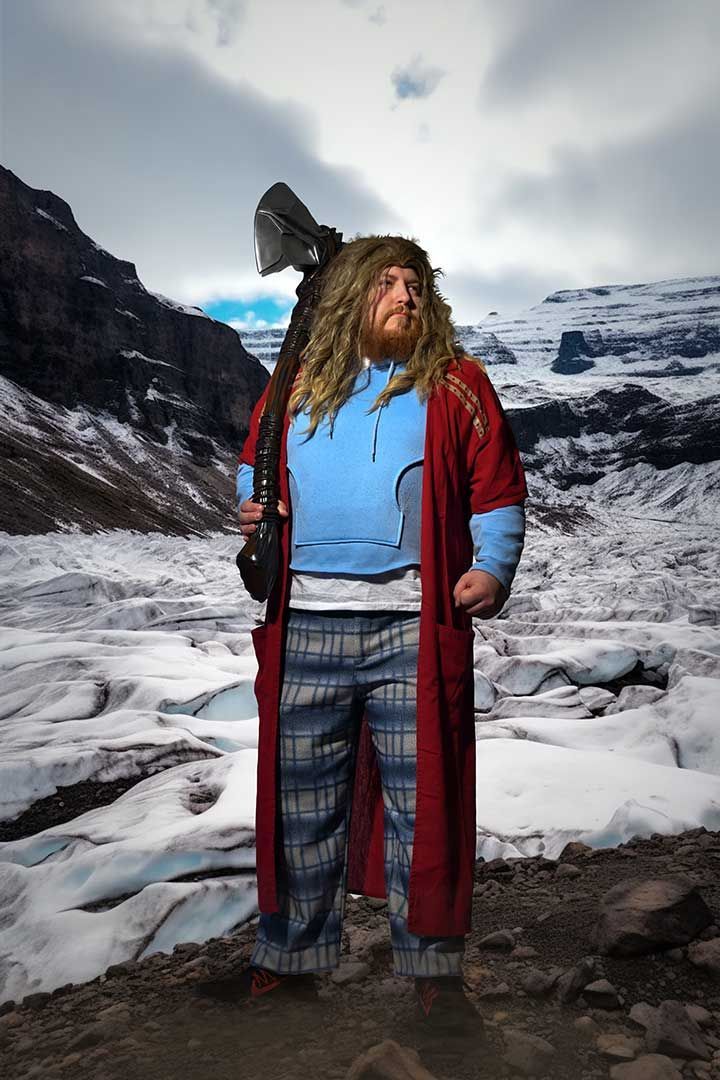 Thor Cosplay in blue shirt and red coat standing on icy ground with snowy mountains behind them