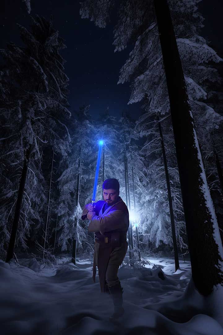 Person holding a glowing purple device in a snowy forest at night under blue lights