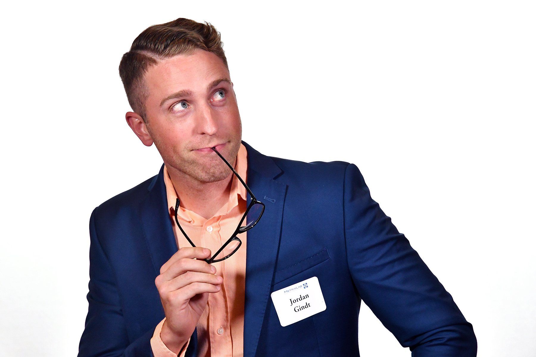 Business Portrait of Man in blue suit holding eyeglasses, looking thoughtfully upward against a white background.
