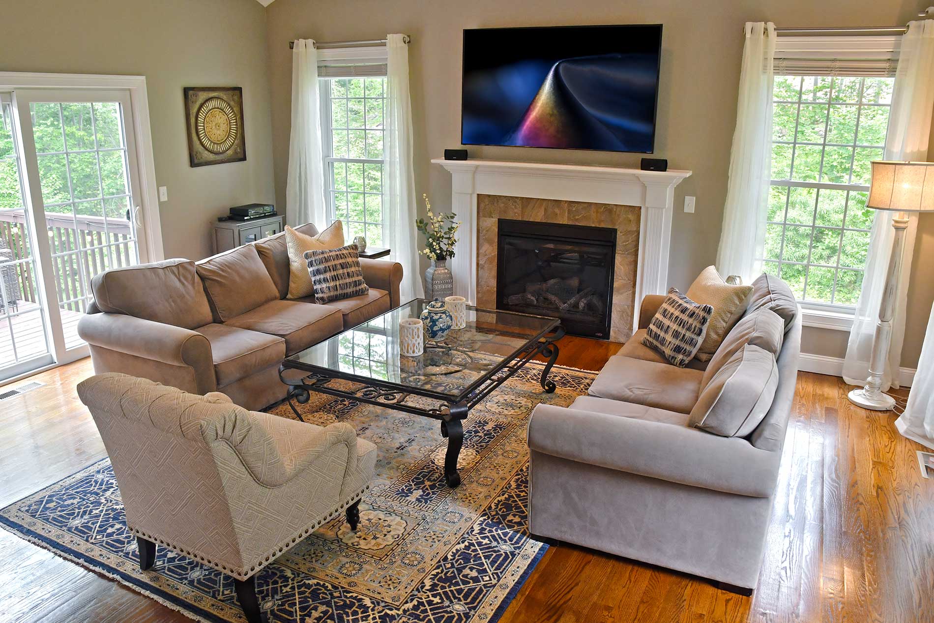 Bright living room with two sofas, glass coffee table, fireplace, and large windows