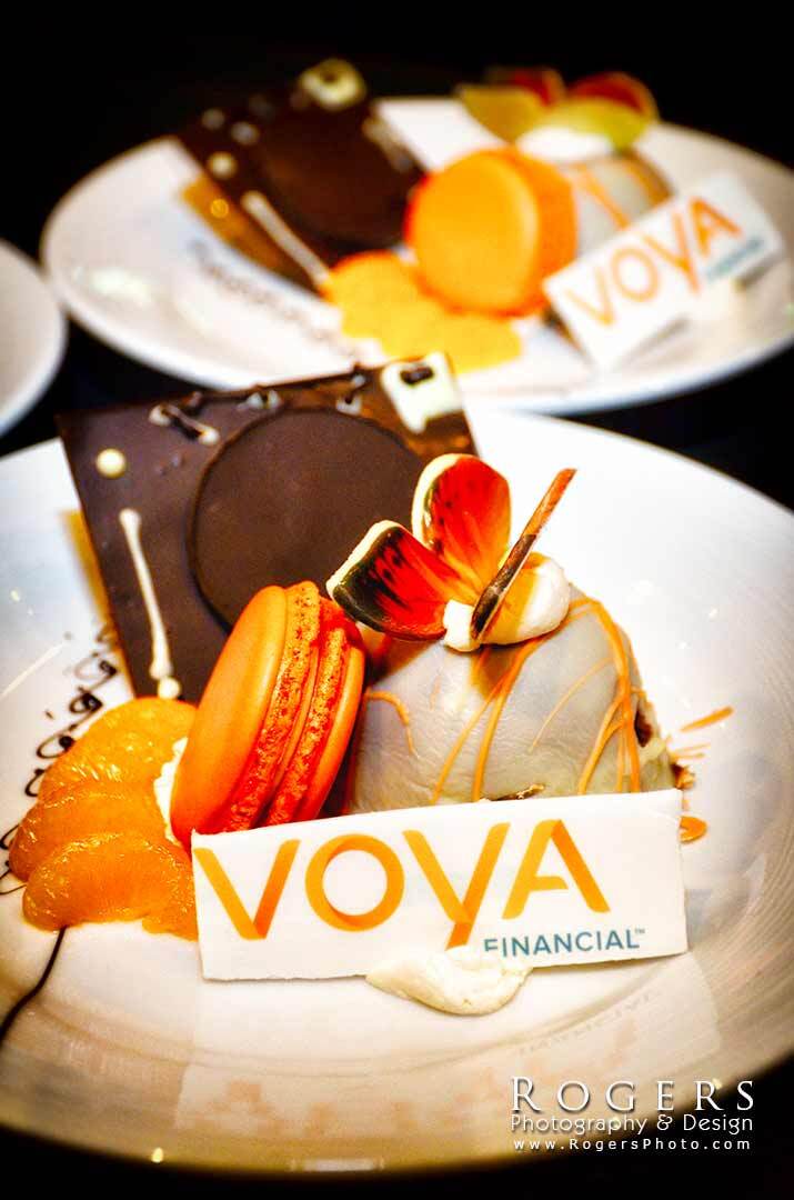 Chocolate dessert plates with orange garnish and VOVA Financial branding on a white tablecloth