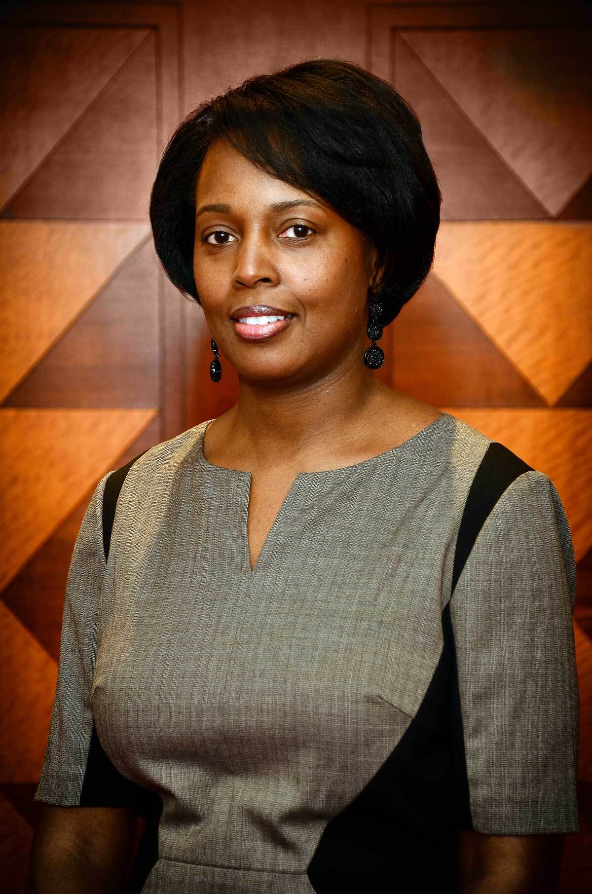 Business Portrait of a smiling woman in a gray dress against a warm geometric backdrop