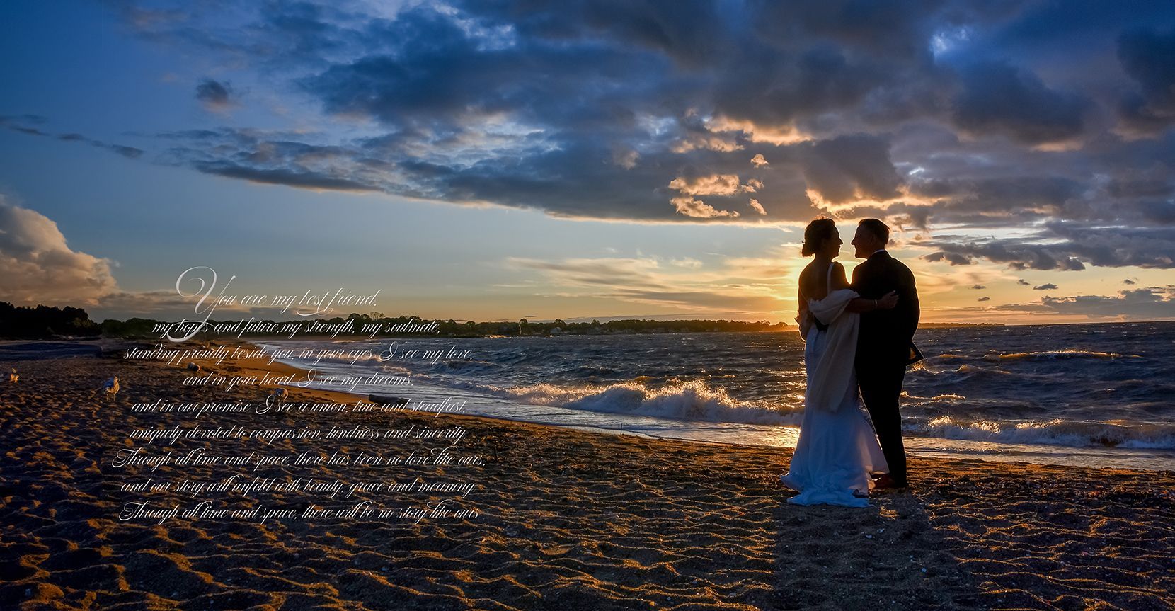 Couple silhouetted on a beach at sunset, standing by the water under a dramatic cloudy sky.