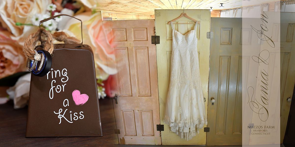 Decorated rustic door display with lace dress, flowers, and a sign reading “Bring on a Kiss”
