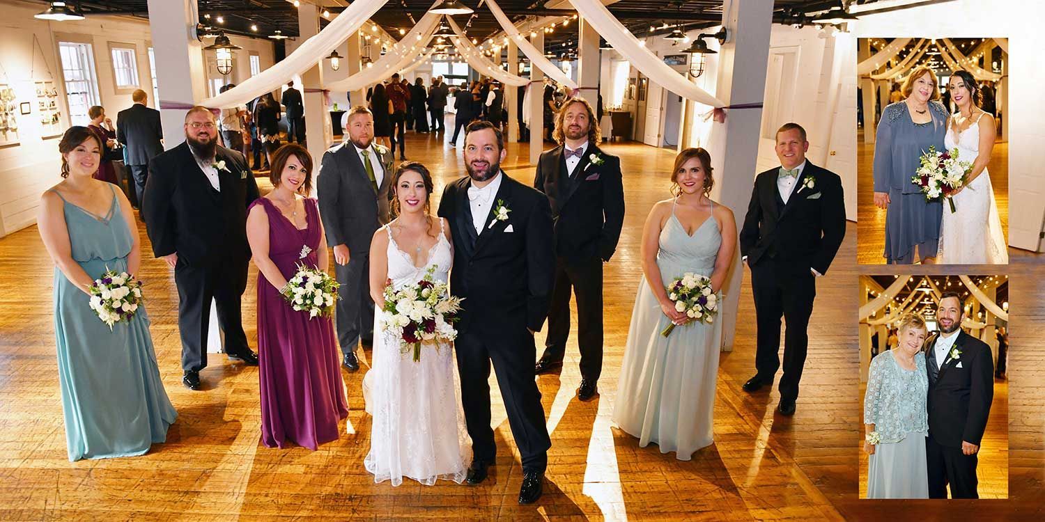 Wedding party posing in a decorated hall, with bride and groom centered among bridesmaids and groomsmen