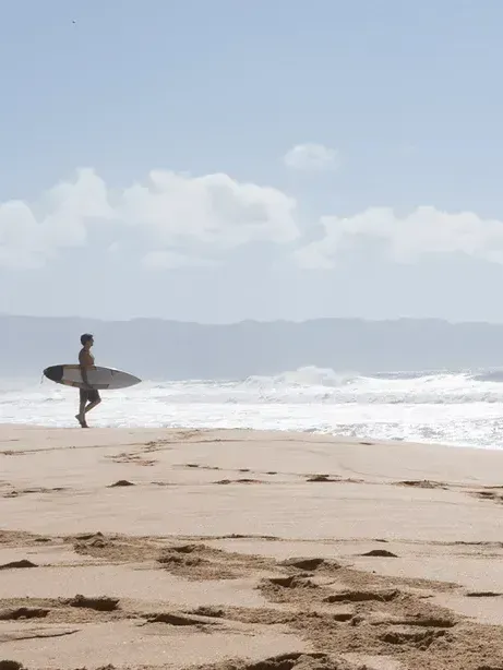 A man is carrying a surfboard on the beach.