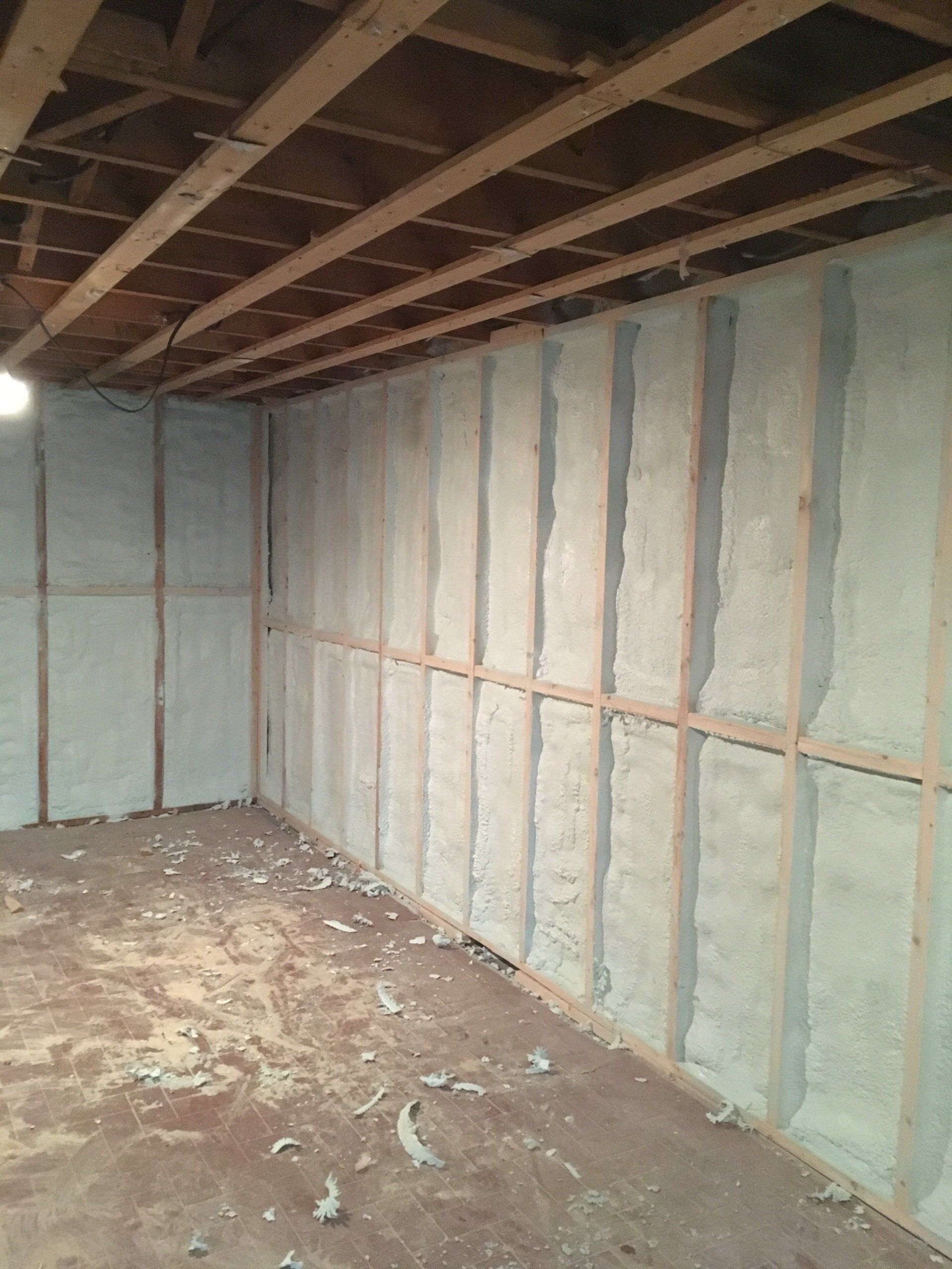 Unfinished room with exposed wall studs, insulation, and debris-covered floor