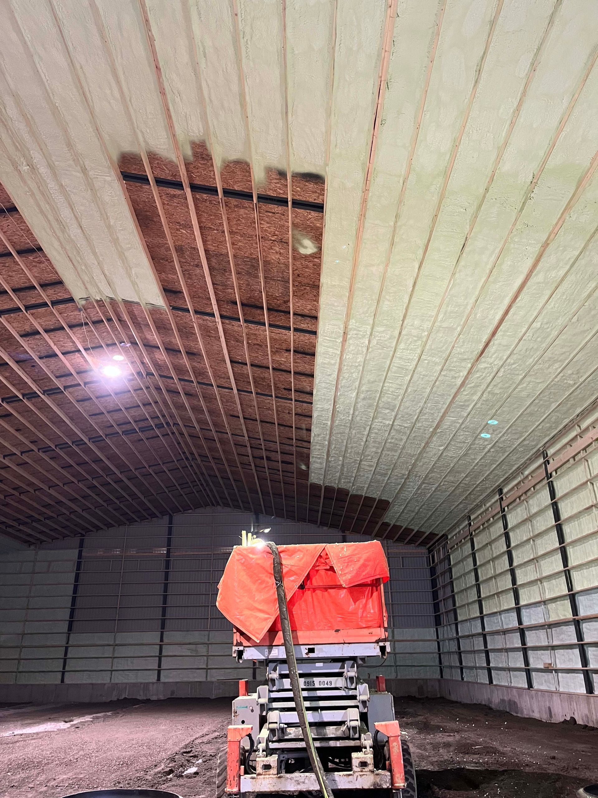 Industrial warehouse interior with a small lift or scissor platform beneath a damaged ceiling panel