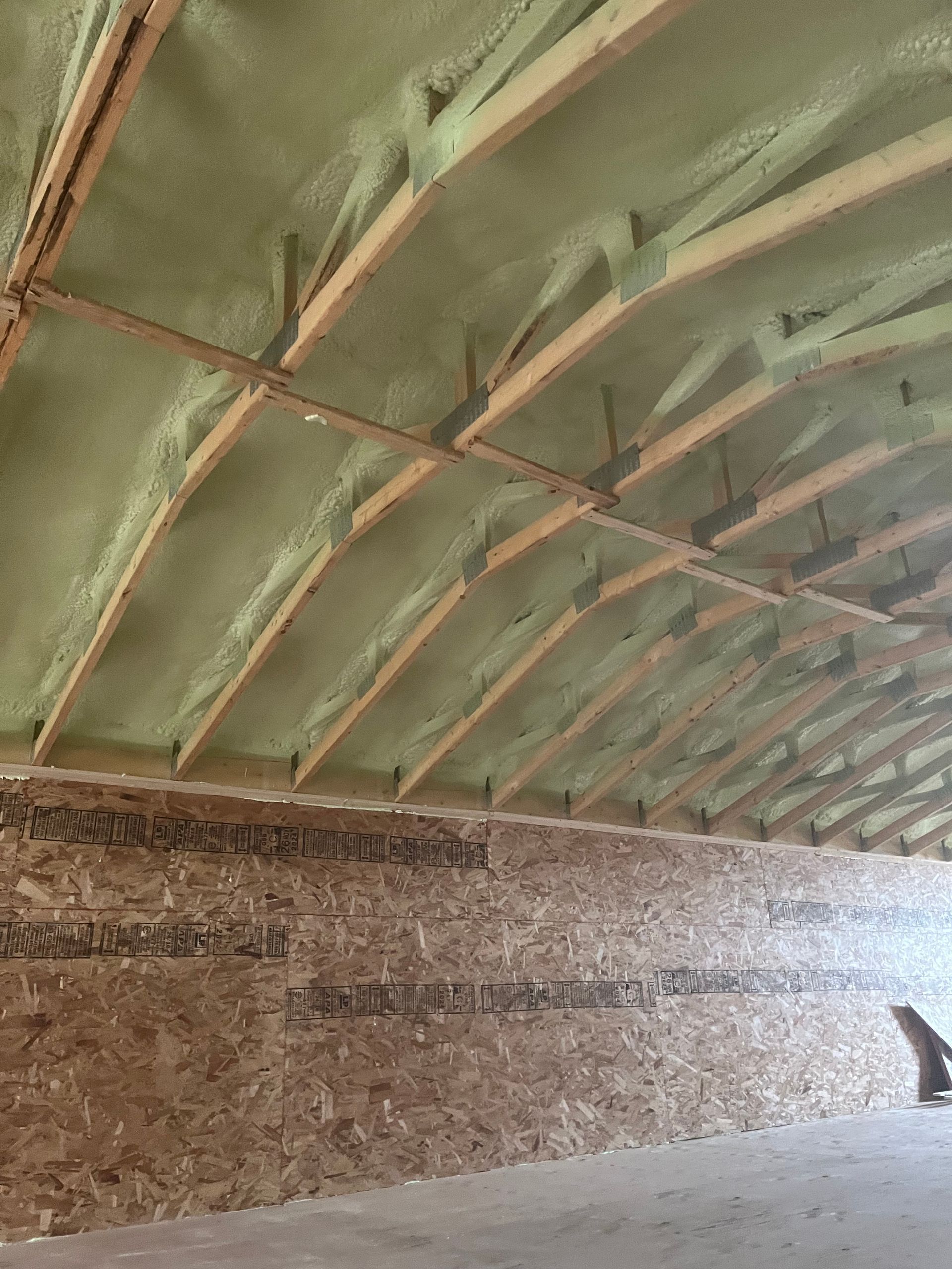 Interior of a rustic barn with a green arched roof and textured wooden walls.