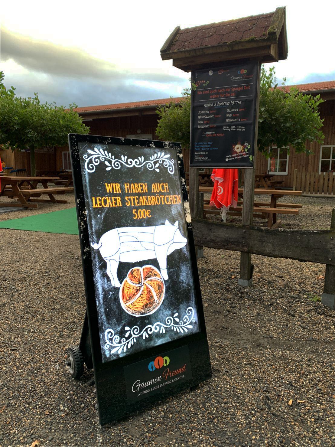 An outdoor restaurant sign with a pig illustration, advertising pork dishes.