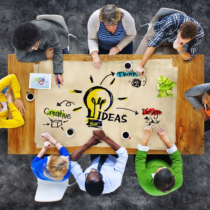 a group of people are sitting around a table with a light bulb