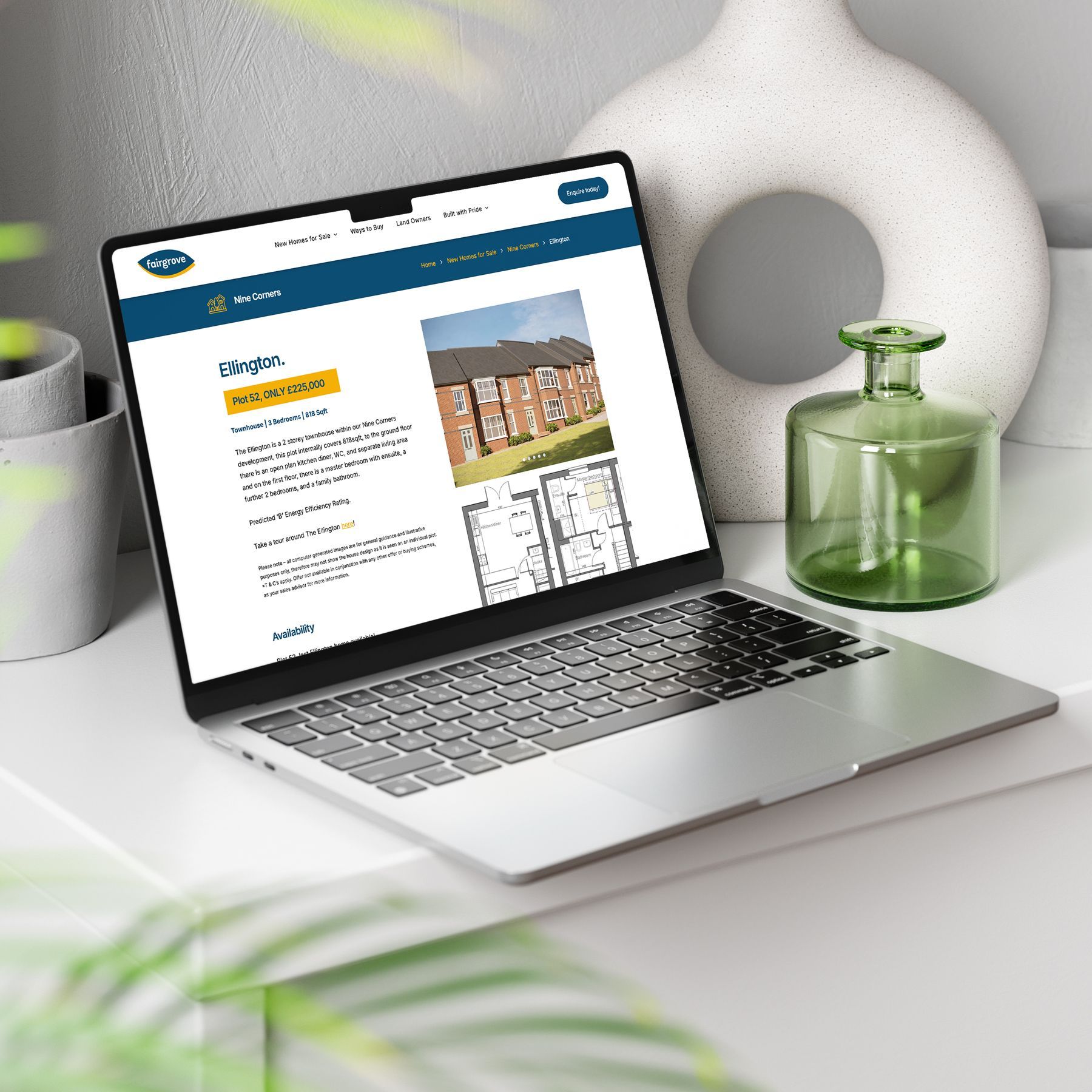 Laptop displaying a website about properties, next to decor and foliage.