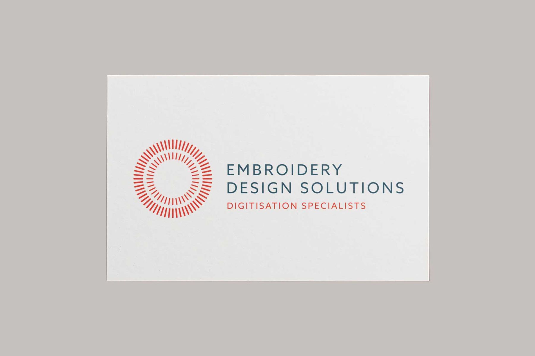 Embroidery Design Solutions logo in red and gray on a white card