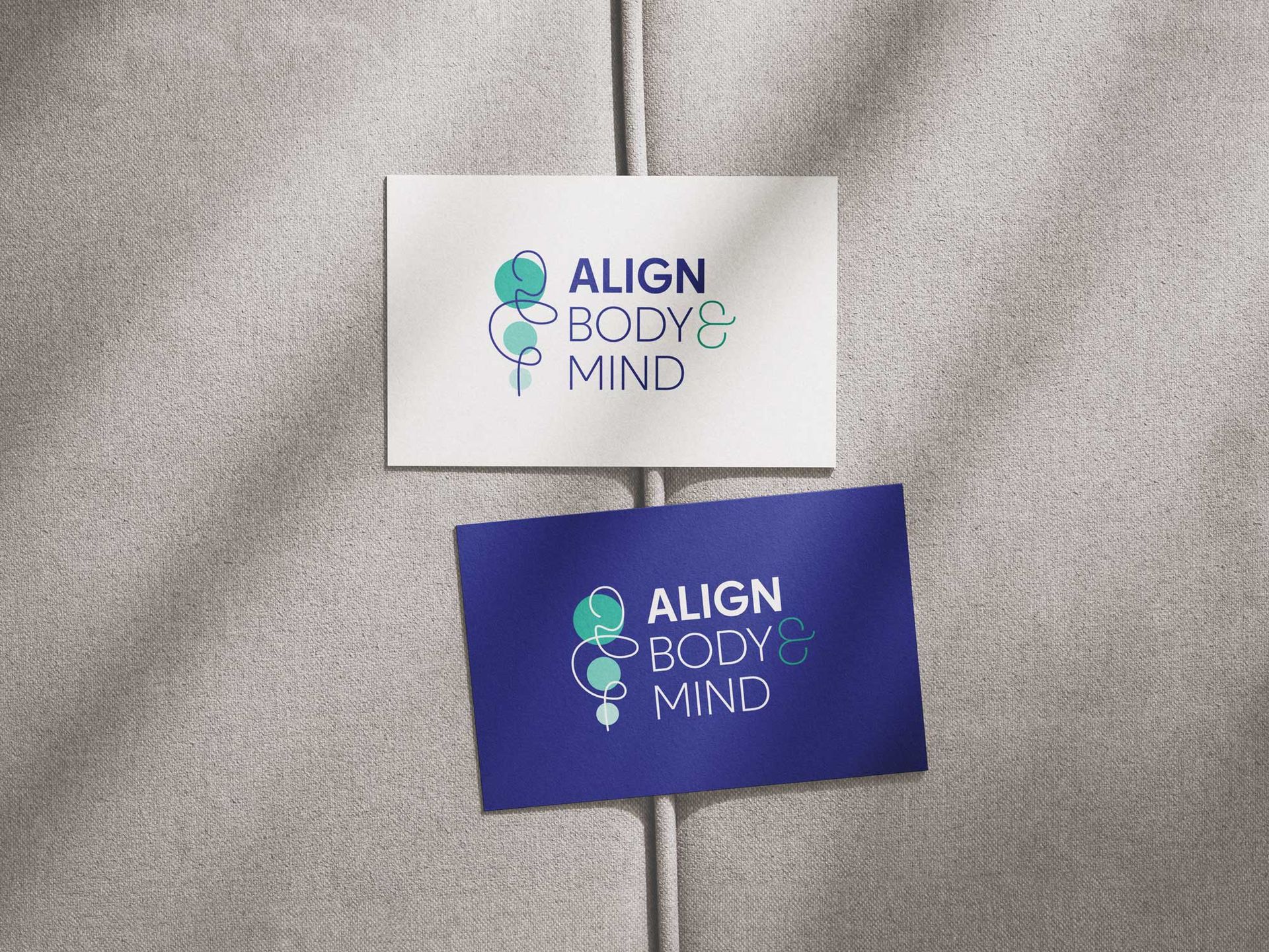 Two ALIGN BODY MIND business cards, one white and one blue, on a textured gray surface