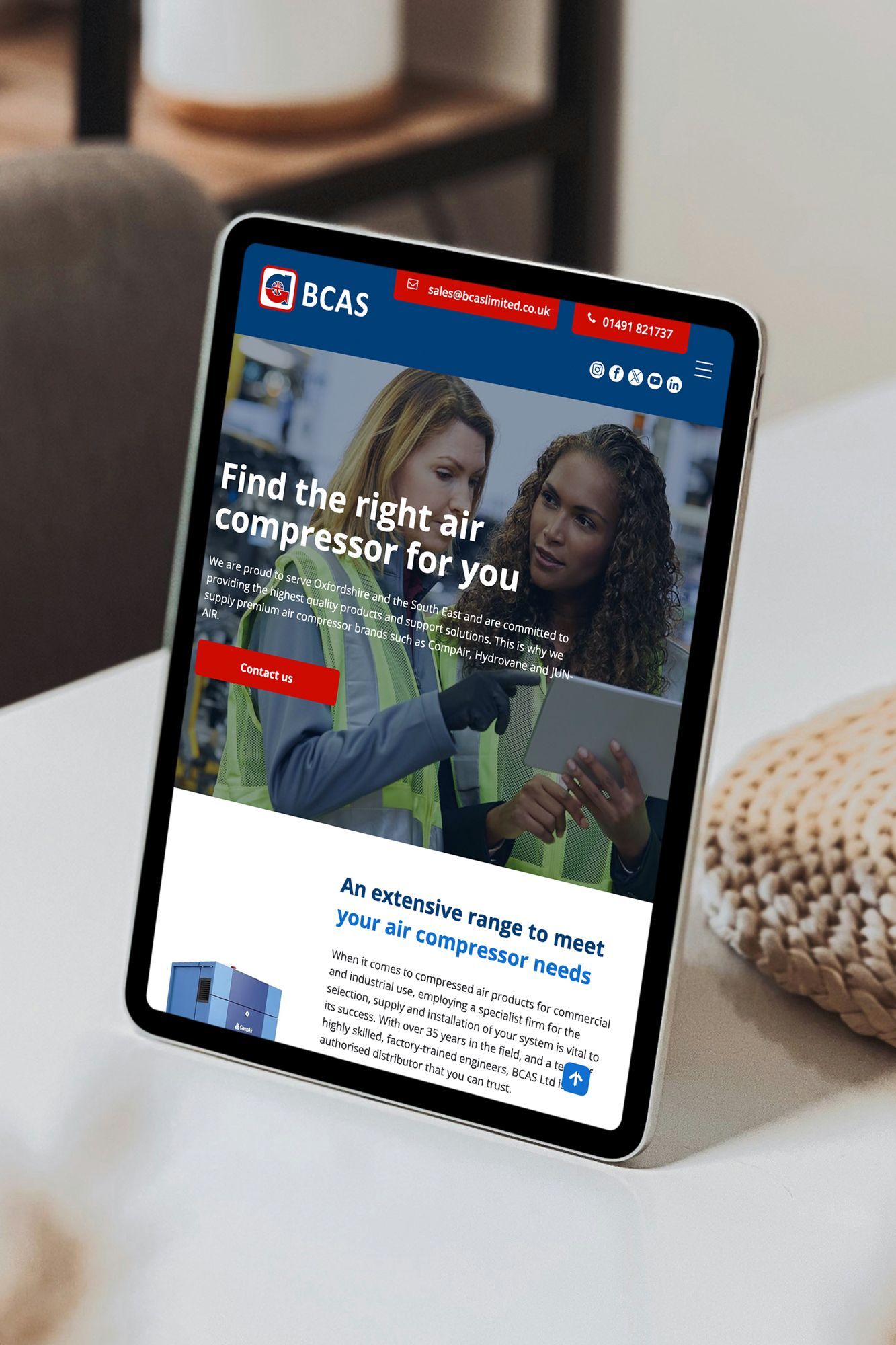 Tablet displaying a website with air compressor information; two women looking at a tablet.