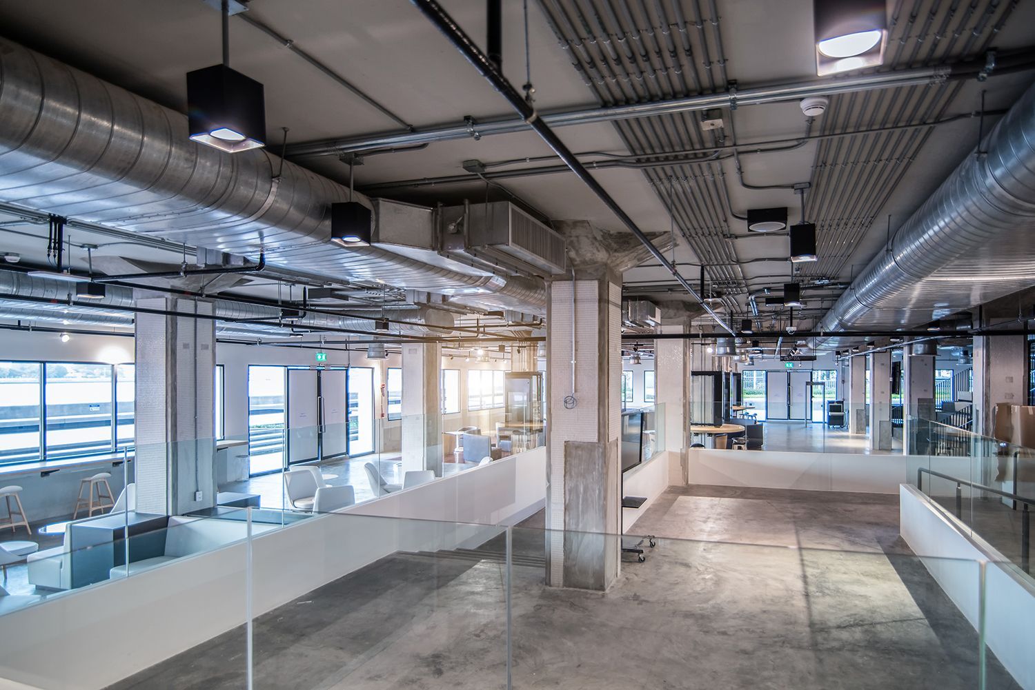 Empty unfinished office interior with exposed ceiling, glass partitions, and concrete floors