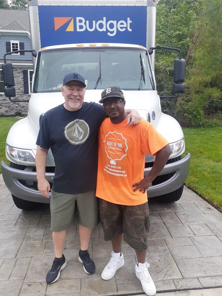 Two men posing in front of a Budget truck, smiling and standing arm in arm.