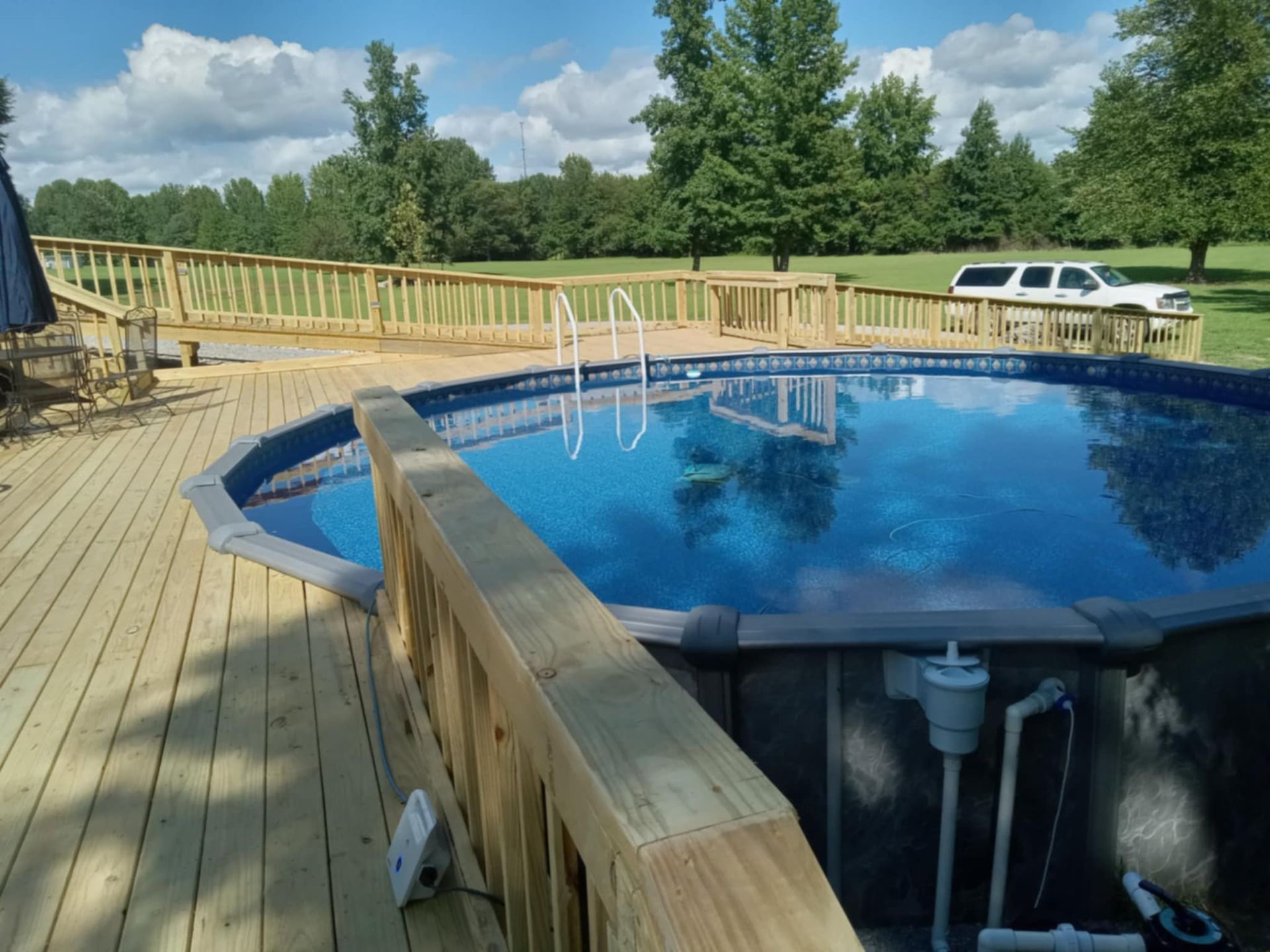 A large swimming pool is surrounded by a wooden deck