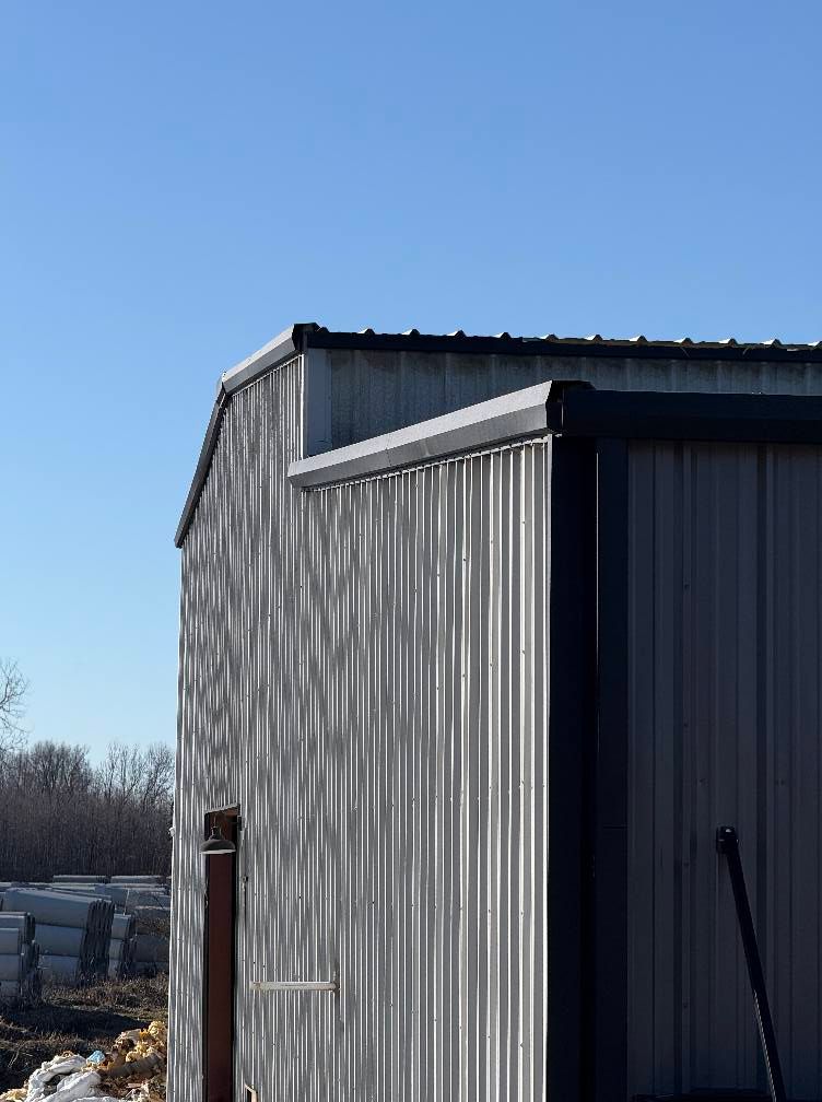 Corrugated metal building with dark trim against a clear blue sky.