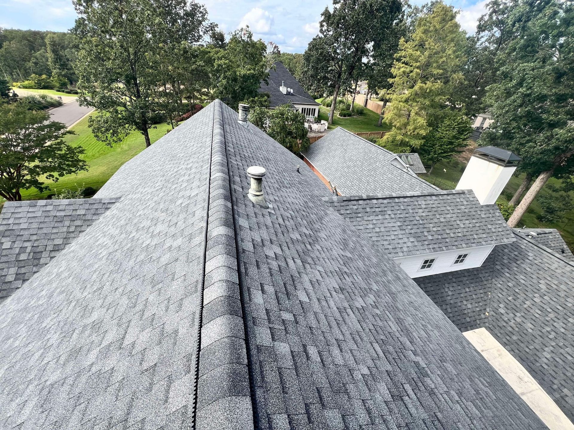 An aerial view of a roof of a house with trees in the background.