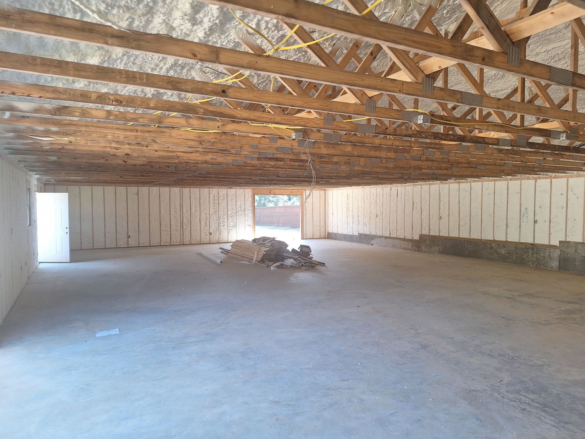 Empty interior of a building under construction. Concrete floor, wooden beams, and walls are visible.